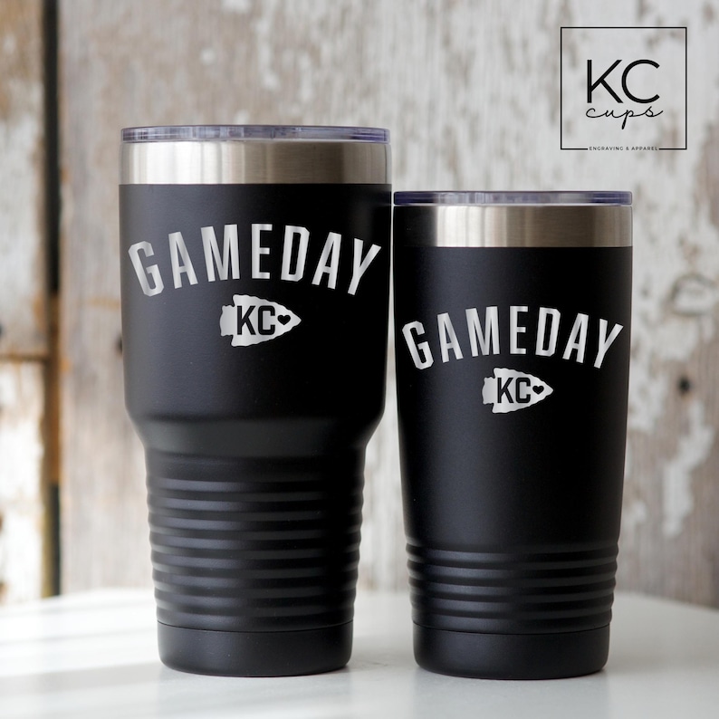May include: Two black stainless steel tumblers with a white inscription that reads "GAMEDAY" with a stylized arrow and the letters "KC".