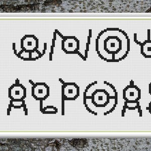Könnte beinhalten: Ein gerahmtes Kreuzstichmuster mit schwarzen, pixeligen Symbolen auf weißem Hintergrund. Die Symbole sind in zwei Reihen angeordnet und ähneln einem Alphabet oder Code. Der Rahmen ist weiß, und der Hintergrund ist eine strukturierte, graue Oberfläche.