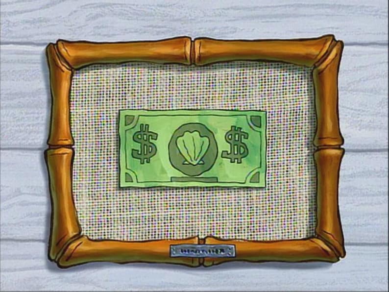 May include: A framed green bill with dollar signs and a seashell emblem. The bill is centered on a woven background within a bamboo-style frame. The frame is a warm, golden brown color.