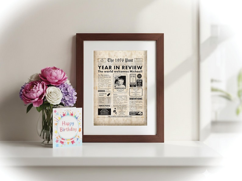 Pu&ograve; includere: Una stampa incorniciata di una pagina di giornale intitolata "The 1976 Post Year in Review". La stampa &egrave; in una cornice marrone, con un bouquet di fiori rosa, bianchi e viola in un vaso e un biglietto di "Buon Compleanno".