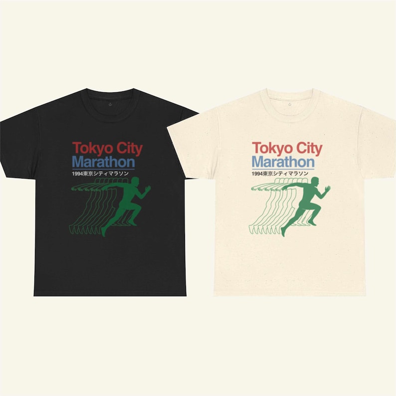 May include: Two t-shirts, one black and one cream, with the text "Tokyo City Marathon" in red and blue, and Japanese text. Each shirt has a green graphic of a running figure. The shirts are likely made of cotton.