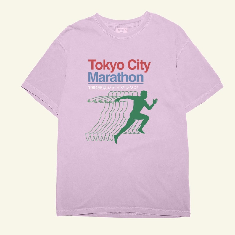 May include: A pale purple t-shirt with the words "Tokyo City Marathon" in red and blue, and Japanese text. A green silhouette of a runner is shown with motion lines, suggesting speed and movement.