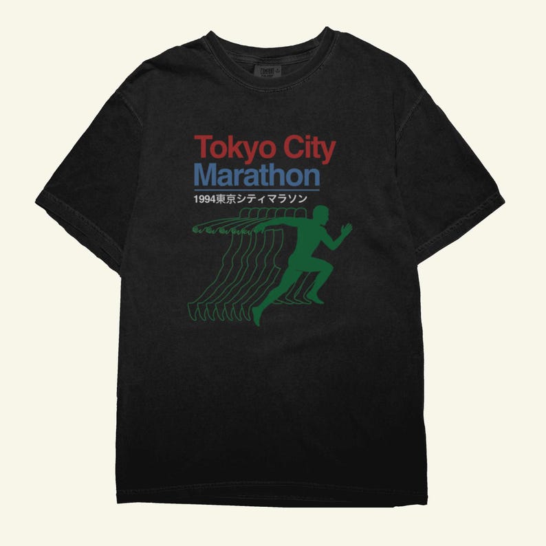 May include: Black t-shirt with the text "Tokyo City Marathon" in red and blue, and the year 1994 below. A green silhouette of a runner is shown with motion lines. The shirt has a crew neck.