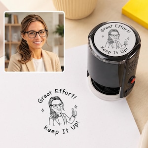 Könnte beinhalten: Ein schwarzer selbstfärbender Stempel mit einer individuellen Karikatur einer Person mit Brille, die den Daumen hochhält. Der Stempelabdruck zeigt Great Effort! Keep It Up! und das gleiche Motiv auf dem Etikett an der Oberseite.