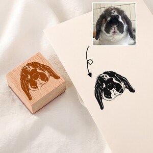 May include: A wooden stamp with a brown and white rabbit illustration. The stamp is used to create a black and white rabbit illustration on paper.