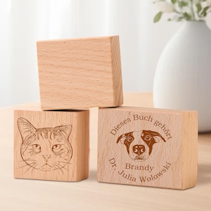 May include: Three wooden blocks with engraved images and text. The top block is blank. The middle block has a line drawing of a cat. The bottom block has a line drawing of a dog and the text "Dieses Buch geh&ouml;rt Dr. Julia Brandy Wolowksi".