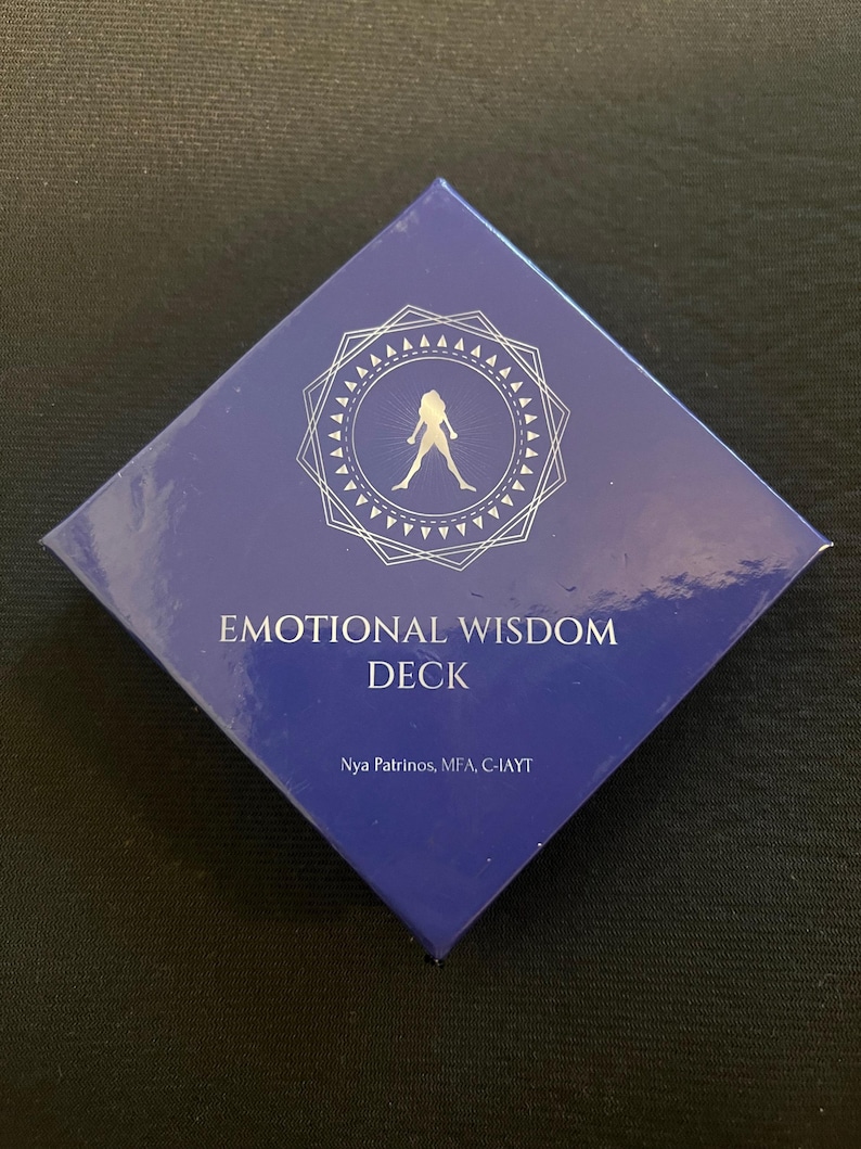 Op de afbeelding: Een donkerblauwe, ruitvormige doos met de woorden "EMOTIONAL WISDOM DECK" in het wit. De doos heeft een zilverkleurig geometrisch ontwerp met een silhouet van een persoon. De naam van de auteur staat ook op de doos.