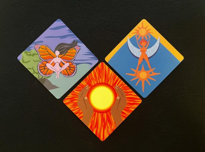 Op de afbeelding: Drie ruitvormige kunstdrukken. E&eacute;n toont een vrouw met vlindervleugels, een andere een vrouw met zon- en maanbeelden, en de derde toont handen die een zon vasthouden. De prints zijn kleurrijk.