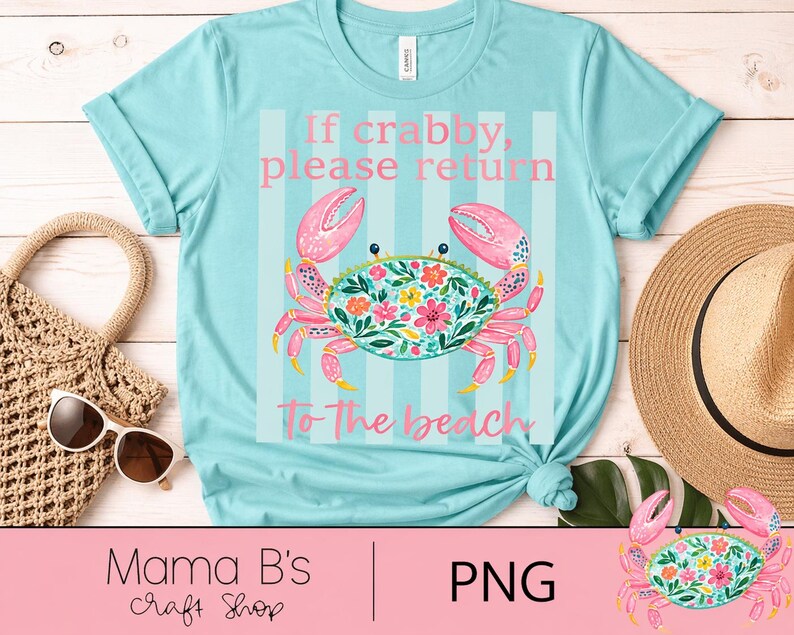 Puede incluir: Una camiseta azul claro con un dise&ntilde;o de cangrejo y el texto "If crabby, please return to the beach." El cangrejo es rosa y turquesa con detalles florales. Un sombrero de paja y gafas de sol est&aacute;n al lado.