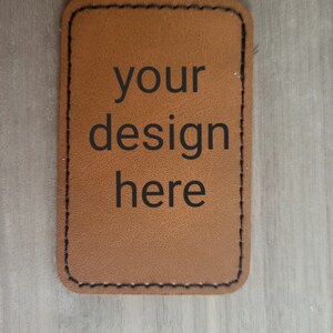 K&ouml;nnte beinhalten: Ein braunes Lederst&uuml;ck mit gen&auml;hten Kanten. Der Text "your design here" ist in Schwarz gedruckt.