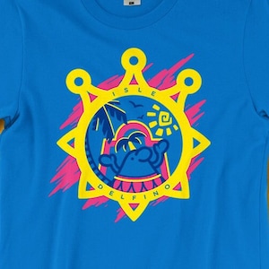 May include: A blue t-shirt with a yellow and pink graphic design featuring a cartoon character on a beach with the text "Isle delfino".