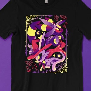 May include: Black t-shirt with a graphic design of two purple and yellow cats wearing witch hats and surrounded by stars and other magical symbols.