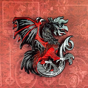 May include: A detailed enamel pin featuring a stylized dragon with black, red, and gray coloring. The dragon has large wings, a feathered chest, and a serpentine tail. The pin is set against a red background.