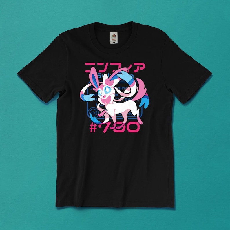 May include: Black t-shirt featuring a Sylveon graphic with Japanese text and the number 700 in pink. The Sylveon character is white and pink with blue accents. The shirt has a crew neck and short sleeves.