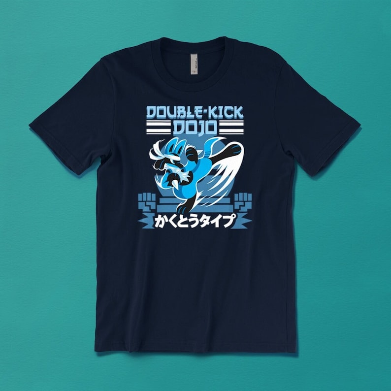 May include: A navy blue t-shirt featuring a blue cartoon character kicking in a fighting stance. The text "DOUBLE-KICK DOJO" is above the character and the text "かくとうタイプ" is below the character.