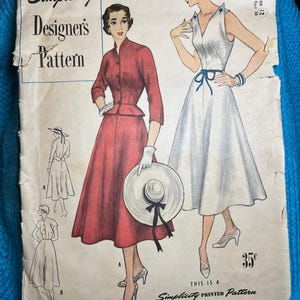 Op de afbeelding: Vintage Simplicity Designer's Pattern 8238 voor een jurk, maat 12, borstomvang 30. Het patroon bevat twee jurkstijlen, een met een rode rok en een witte kraag, en de andere met een witte rok en een blauwe strik. Het patroon kost 35 cent.