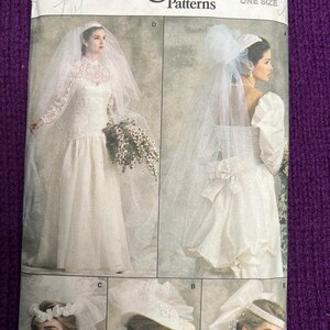 May include: Vogue Patterns wedding dress sewing pattern. The pattern features a bridal gown with long sleeves, a full skirt, and a veil. The cover also shows different bridal headwear options. The pattern is labeled "ONE SIZE".