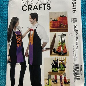 May include: A sewing pattern for Halloween crafts. The pattern includes instructions for making an apron, a pumpkin, a witch's legs, a cat, and an owl. The pattern is for adults and includes sizes small, medium, large, and extra large. The pattern number is M6415.