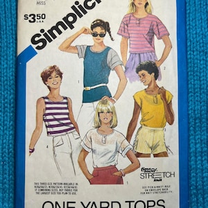 May include: Vintage Simplicity sewing pattern for one-yard tops, size K (8, 10, & 12). The pattern features illustrations of various top designs, including striped and solid color options. The cover has the text "ONE-YARD TOPS".