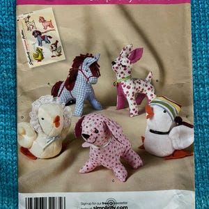 May include: Simplicity sewing pattern featuring stuffed animal designs. The pattern includes instructions for creating a horse, deer, dog, duck, and a lion. The pattern envelope is labeled "2763" and "One Size".