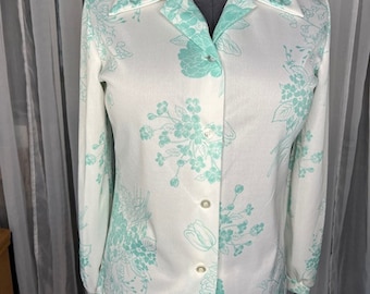 Puede incluir: Una camisa blanca de manga larga con botones y un estampado floral verde claro.