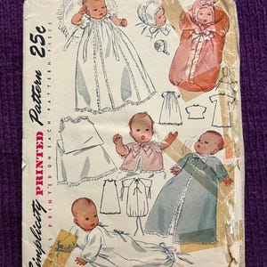 Könnte beinhalten: Vintage Simplicity Schnittmuster 2656 für Babykleidung. Das Muster zeigt Illustrationen von Babykleidern, Mützen und einem Bademantel. Das Muster ist auf Papier gedruckt und enthält den Text "One Size" und "25c".