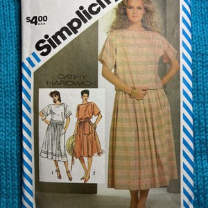 May include: Simplicity sewing pattern featuring a two-piece outfit. The pattern includes a top and skirt with a striped design. The package has the text "Cathy Hardwick" and the price is $4.00.