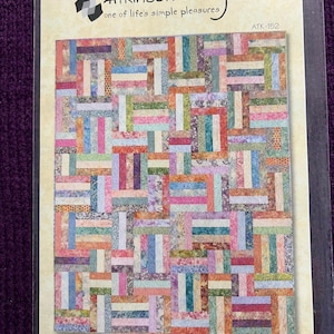 May include: A package displaying a colourful quilt pattern named "Popsicle Sticks" by Atkinson Designs. The quilt design features rectangular blocks in shades of pink, blue, green, and orange.