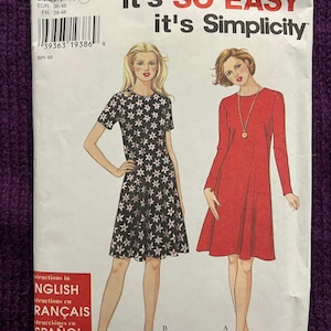 Puede incluir: Un patrón de costura Simplicity con ilustraciones de dos vestidos. El patrón incluye el texto "It's SO EASY it's Simplicity" e información de tallas. Los vestidos son un estampado floral negro y un diseño rojo liso.