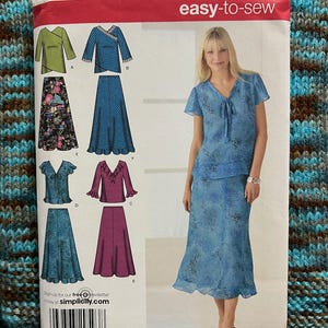 Puede incluir: Patrón de costura Simplicity easy-to-sew 4221. El patrón presenta varios diseños de faldas y tops, incluyendo un conjunto de falda y top floral azul. Tallas BB 20W-28W, EUR 46-54 y FR 48-56. Una mujer lleva un conjunto floral azul.