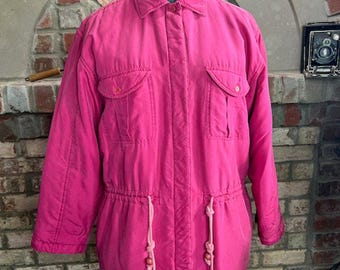 May include: A bright pink jacket with a button-up front, two flap pockets, and a drawstring waist. The jacket has pink and white cords with pink beads.