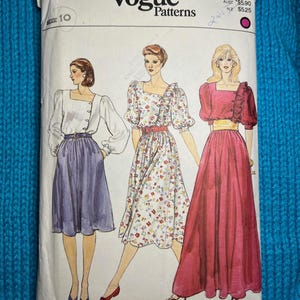 May include: Vogue Patterns sewing pattern packet featuring illustrations of three different dress designs. The packet is white with the Vogue Patterns logo and the number 8256. The dresses include a white blouse and purple skirt, a floral dress, and a red dress.