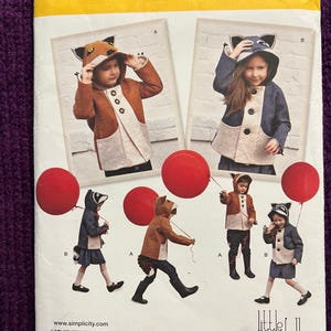 May include: Simplicity pattern 1477A features children's hooded jackets with animal-themed designs. The pattern includes sizes 3-8. The jackets have a fox, raccoon, and other animal designs. The pattern includes the text "Simplicity" and "little goodall".