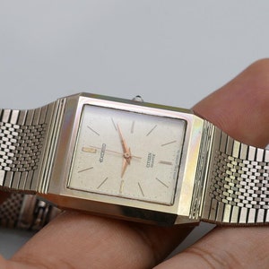 May include: A silver Citizen Quartz Exceed watch with a square face and a silver mesh band.
