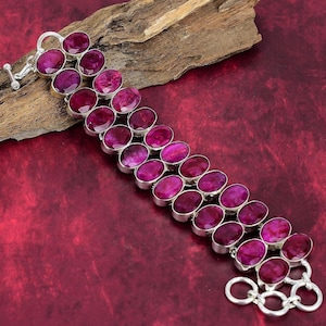 Op de afbeelding: Een zilveren armband met een dubbele rij ovale roze edelstenen. De armband heeft een sluiting.