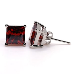 May include: A pair of silver stud earrings with square red gemstones.