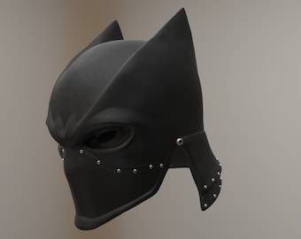 May include: A black helmet with a pointed top and a face mask. The helmet has a textured surface and is decorated with silver studs.