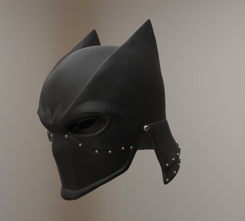 May include: A black helmet with a pointed top and a face mask. The helmet has a textured surface and is decorated with silver studs.