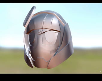 Puede incluir: Un casco plateado y marrón con una visera y una pequeña antena en la parte superior. El casco tiene un diseño futurista y parece estar hecho de metal.