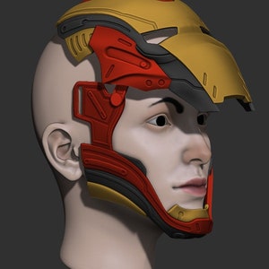 Pode incluir: Um capacete impresso em 3D vermelho, amarelo e preto com uma máscara facial. O capacete é projetado para parecer o capacete de um super-herói.