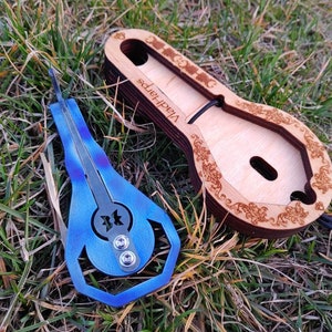 May include: A blue metal  'Vihart Harps'  karimba with a decorative design and a wooden case with a floral pattern.
