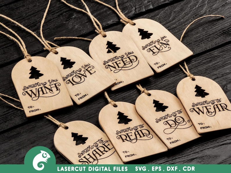 K&ouml;nnte beinhalten: Zehn h&ouml;lzerne Geschenkanh&auml;nger mit einem Weihnachtsbaumdesign und dem Text "Something you..." gefolgt von einem anderen Wort auf jedem Anh&auml;nger. Die W&ouml;rter sind: Want, Love, Need, Fun, Share, Read, Do, Wear.