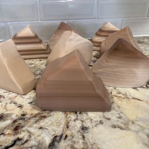 May include: A set of six wooden geometric shapes in various shades of brown. The shapes are all triangular and have a smooth, polished finish.