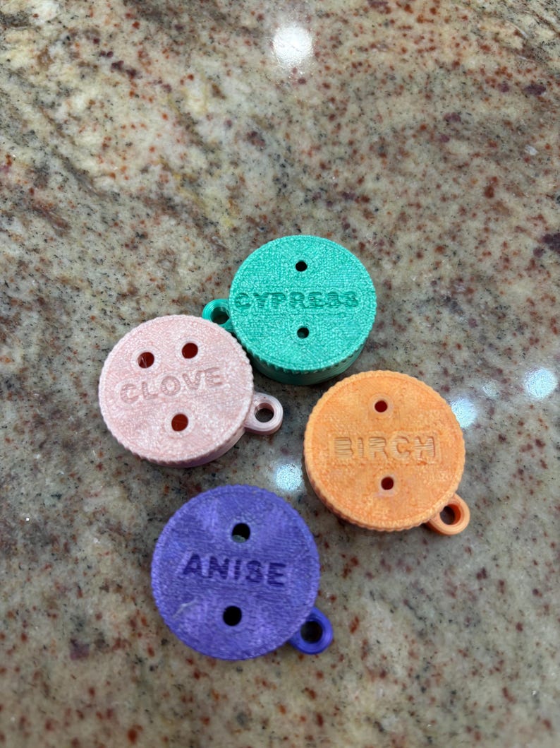 May include: Four small, round, colourful, scented discs with holes and a string attached. The discs are labelled "Anise", "Birch", "Clove", and "Cypress".