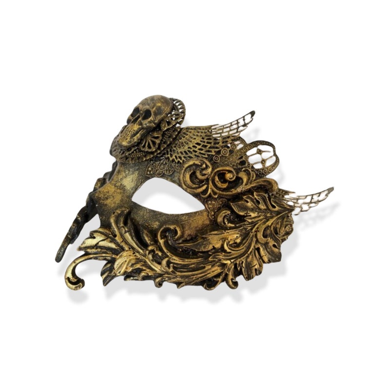 Op de afbeelding: Een goud en bronskleurig masker met een schedel. Het masker heeft ingewikkelde filigraan- en bloemmotieven. Het metalen masker heeft een verweerde afwerking, waardoor het een vintage uitstraling heeft. Oogmasker.