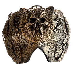 Puede incluir: Una m&aacute;scara de carnaval dorada con un dise&ntilde;o de calavera y mariposa. La m&aacute;scara est&aacute; hecha de metal y tiene un dise&ntilde;o delicado e intrincado.