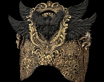 May include: A decorative headpiece featuring an intricate gold filigree base with ornate floral patterns. The center is adorned with a sculpted black eagle emblem flanked by two large, detailed black feathered wings extending outward on each side.