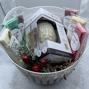 May include: A white wicker basket filled with a variety of scented wax melts and a white ceramic plug-in fragrance warmer. The wax melts are in various colors and have different scents, including "Blackberry & Bay Leaf" and "Cranberry Prosecco". The warmer is in a box with the text "Plug-in Fragrance Warmer" on it.