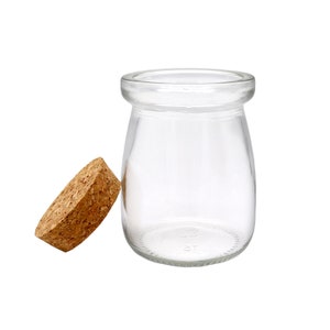 May include: A clear glass jar with a cork lid. The jar is empty and has a rounded bottom.