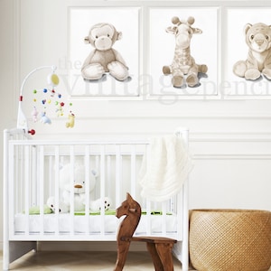 May include: A white crib with a white stuffed animal inside. There are three framed prints on the wall above the crib. The prints feature a monkey, a giraffe, and a tiger. The prints are all in shades of brown and white.